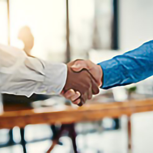 Zwei Personen schütteln sich die Hände in einer geschäftlichen Umgebung. Symbolbild für Amgen Direct, dem Bestell-Portal für Kundinnen und Kunden .