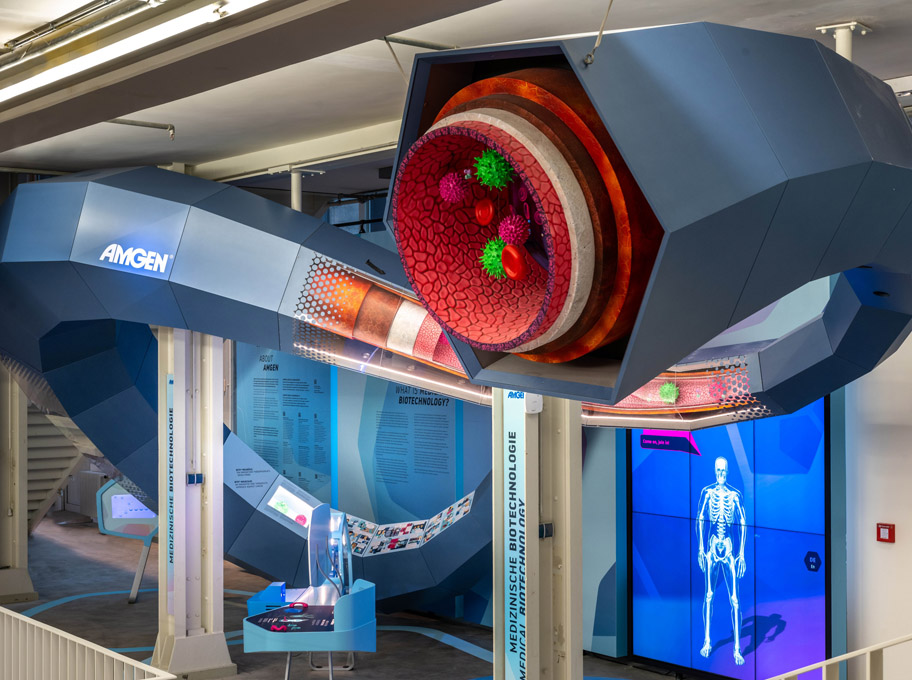 Innenaufnahme einer modernen Ausstellung mit einer großen, blauen geschwungenen Skulptur mit rotem Leuchtelement.